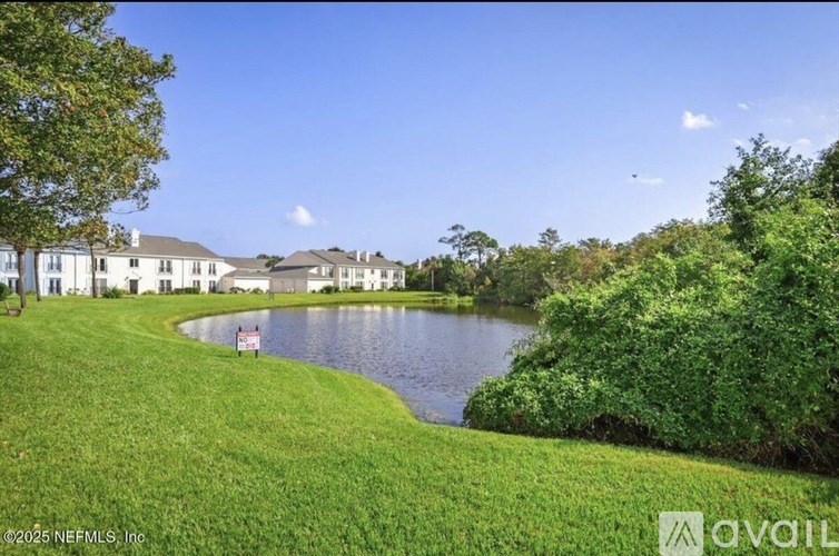 A serene landscape with a lake, houses, and lush greenery.