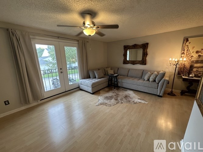 A living room with a grey couch and a rug on the floor.