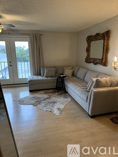 A living room with a grey couch, a mirror, and a rug.
