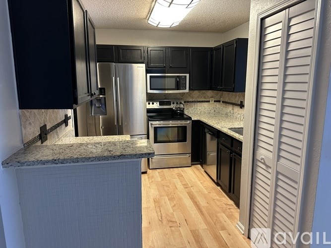 A kitchen with black cabinets and stainless steel appliances.