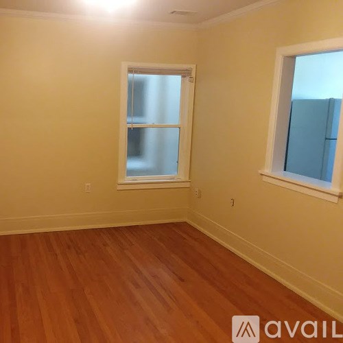 A room with wooden floors and two windows.