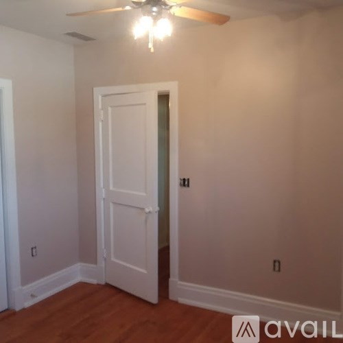A room with a white door and a ceiling fan.