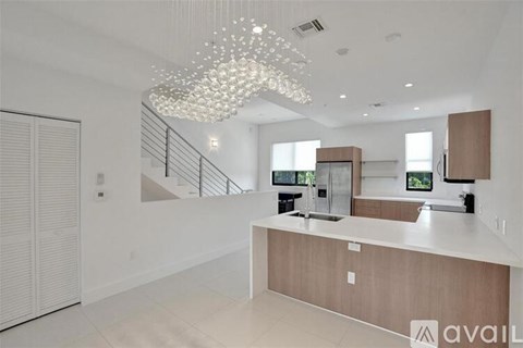 A modern kitchen with a wooden counter and a chandelier hanging from the ceiling.