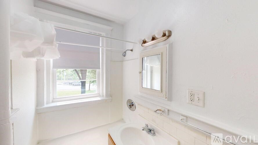 A white bathroom with a window and a tub.
