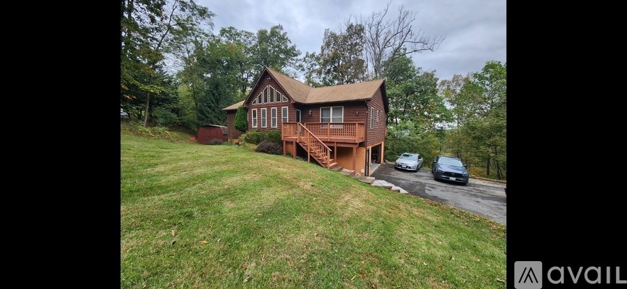 A house with a brown roof and a deck is surrounded by green grass.