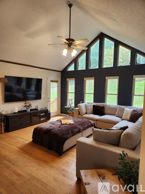 A living room with a brown sofa and a ceiling fan.