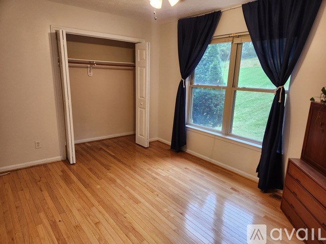 A room with a sliding door and a window with black curtains.