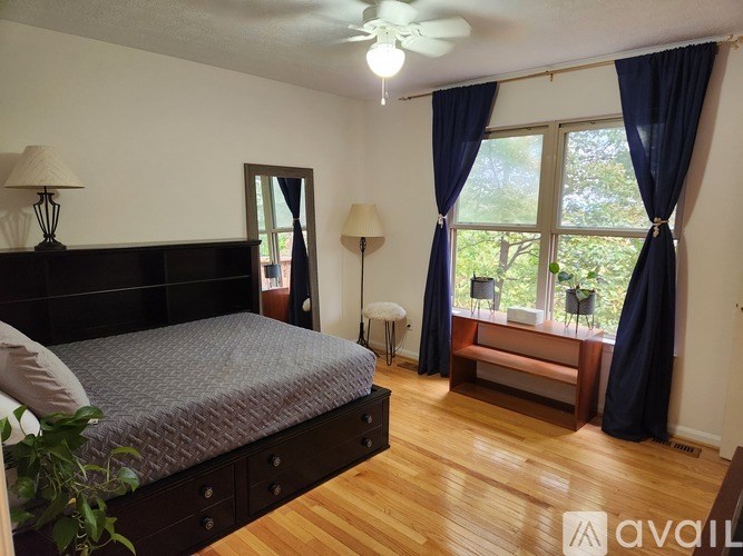 A bedroom with a large bed and a window with blue curtains.