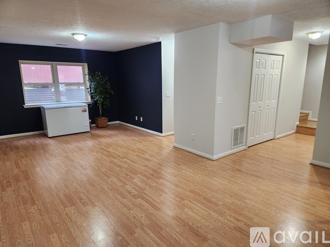 A room with wooden flooring and a white refrigerator.
