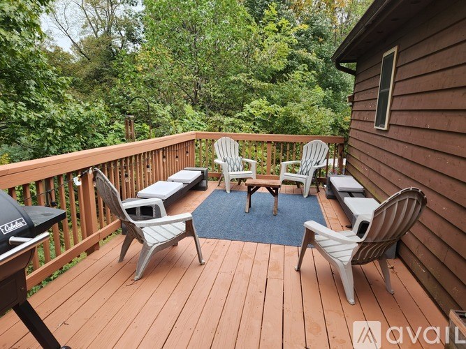 A wooden deck with chairs and a table surrounded by trees.