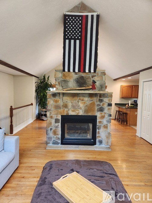 A living room with a stone fireplace and an American flag hanging above it.