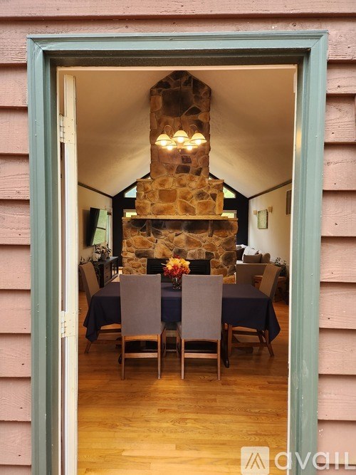 A dining room with a stone fireplace and wooden chairs.