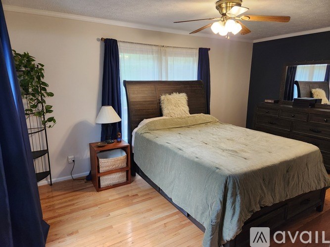 A bedroom with a bed, nightstand, and a ceiling fan.