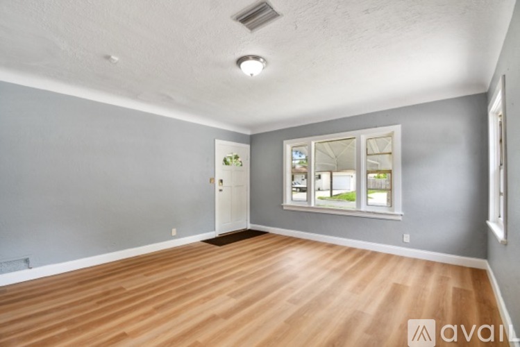 A room with wooden flooring and a window with a view of a building outside.
