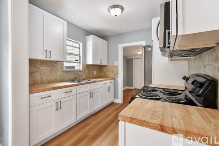 A kitchen with white cabinets and a wooden countertop.