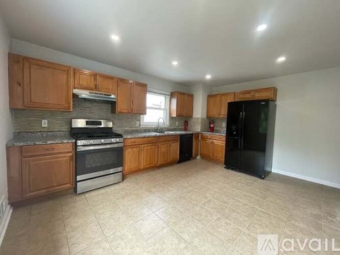 A kitchen with wooden cabinets and a black refrigerator.