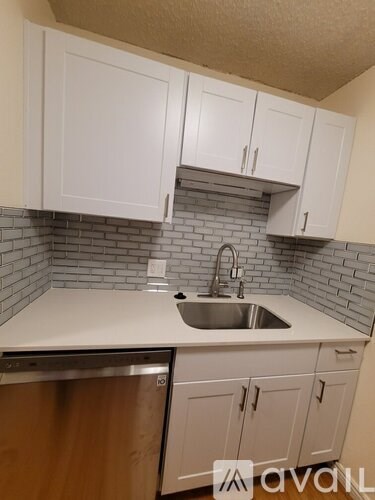A kitchen with white cabinets and a stainless steel dishwasher.