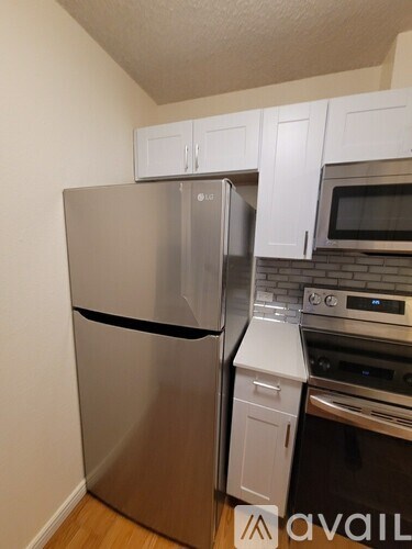 A kitchen with a stainless steel refrigerator and white cabinets.