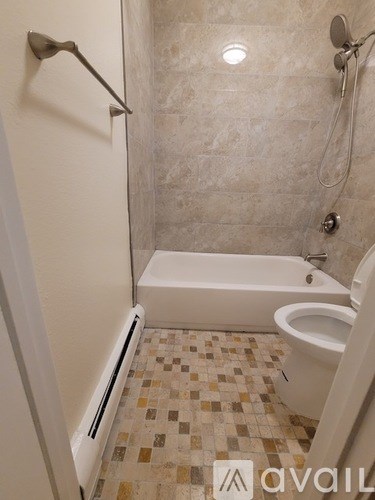 A bathroom with a white tub and tiled floor.