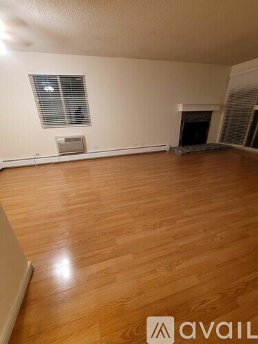 A room with wooden flooring and a fireplace.