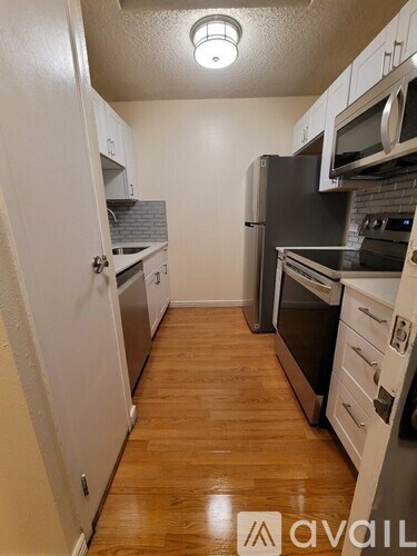 A kitchen with wooden floors and white cabinets.