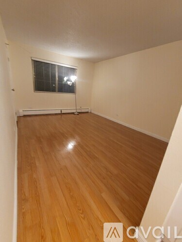 A room with wooden flooring and a window with blinds.