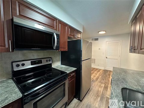 A kitchen with a black refrigerator and stove top oven.