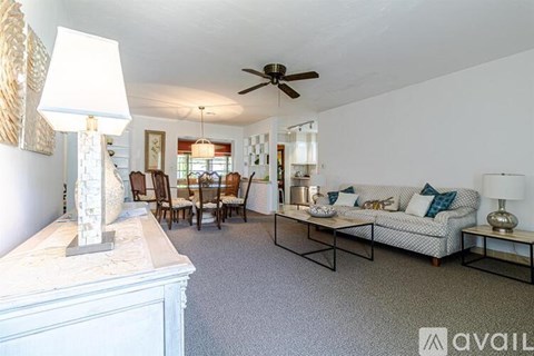 A living room with a white couch and a marble top table.