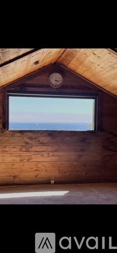 A wooden room with a window showing the sky.