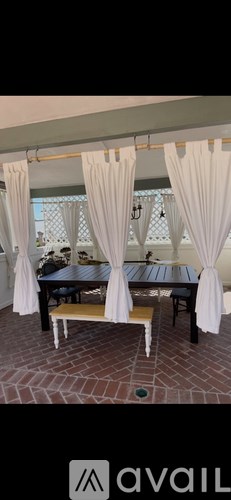 A table with white curtains is set up for an outdoor meal.