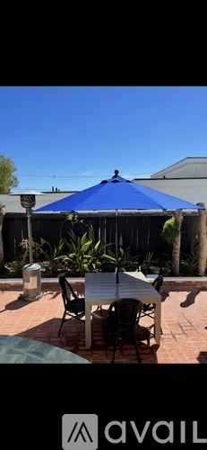 A patio with a table and chairs under a blue canopy.