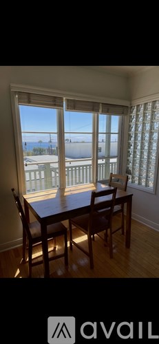 A dining room with a table and chairs and a window overlooking a balcony.
