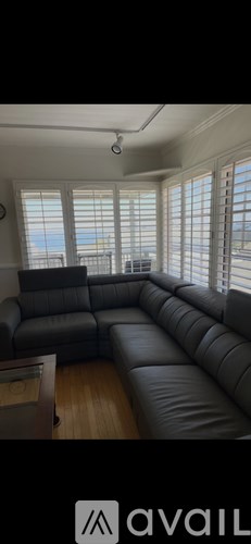 A living room with a grey leather sofa and a ceiling fan.