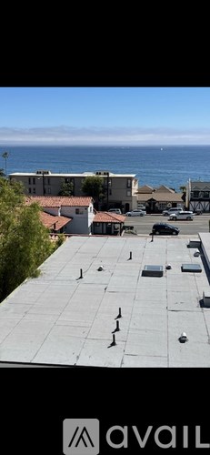 A view of a rooftop with a building and the ocean in the background.