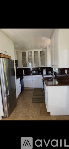 A kitchen with white cabinets and a refrigerator.