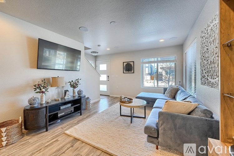 A living room with a grey couch, a wooden cabinet, and a flat screen TV mounted on the wall.
