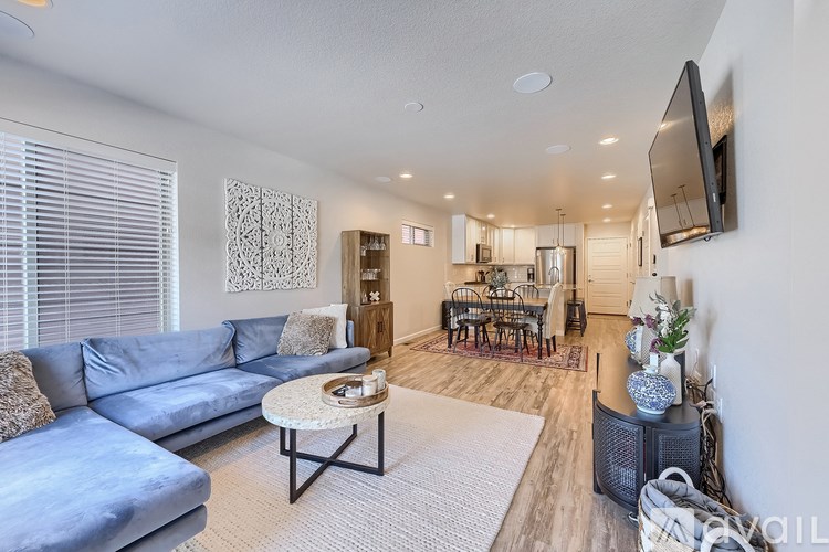 A living room with a blue couch and a television mounted on the wall.