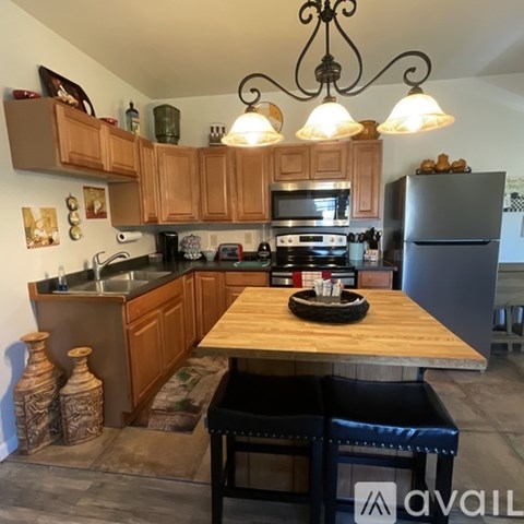A kitchen with wooden cabinets and a black fridge.