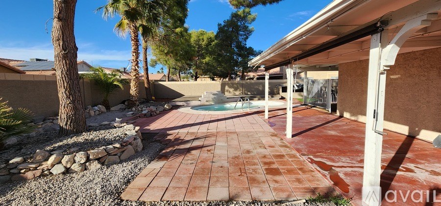 A patio with a pool and a stone wall.