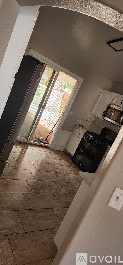 A kitchen with a black refrigerator and white cabinets.