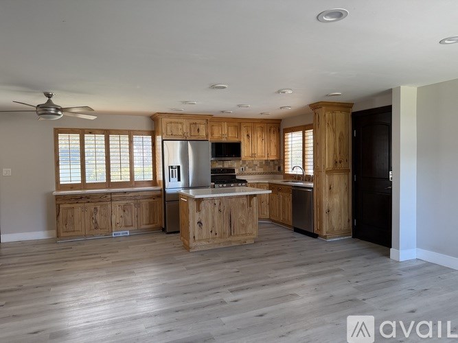 A spacious kitchen with wooden cabinets and a ceiling fan.