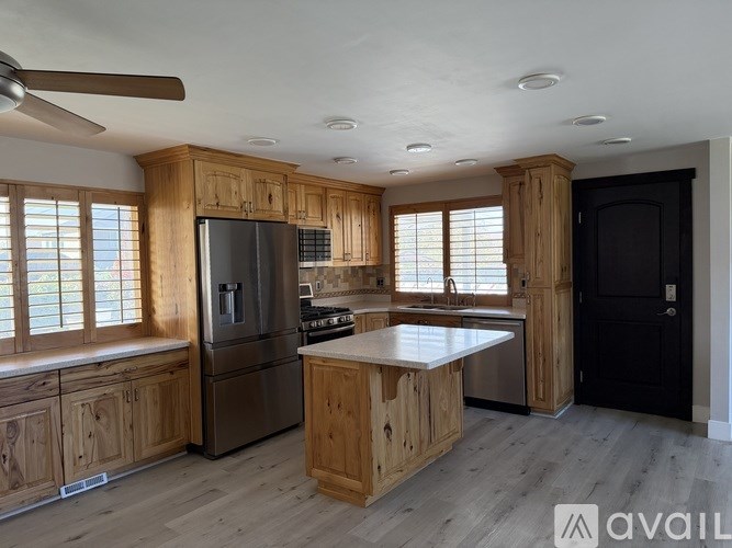 A kitchen with wooden cabinets and a stainless steel refrigerator.