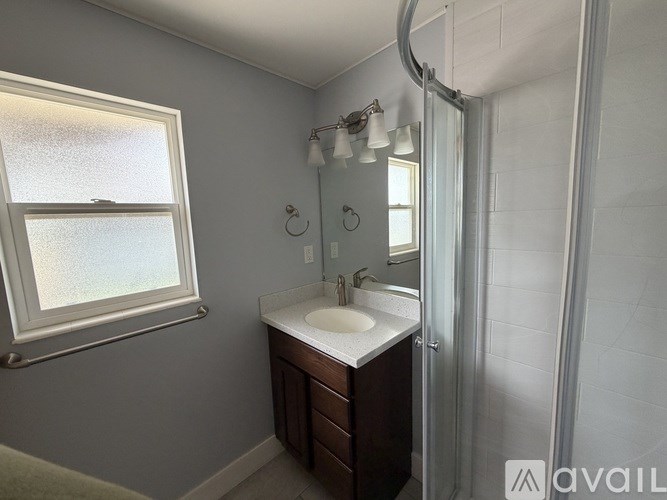 A bathroom with a sink, mirror, and shower.