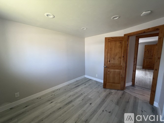 A room with wooden flooring and a door on the right side.