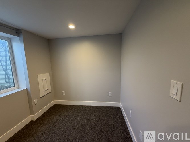 A room with a carpeted floor and a window on the left side.