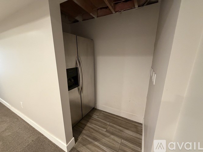 A kitchen area with a stainless steel refrigerator and wooden flooring.