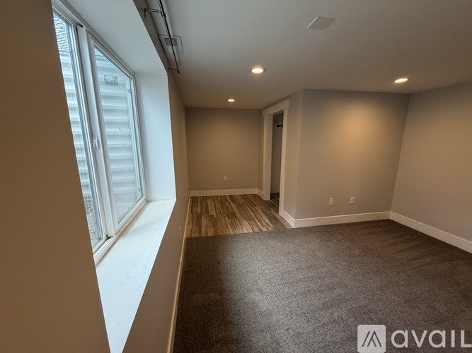 A room with a carpeted floor and a window on the left side.