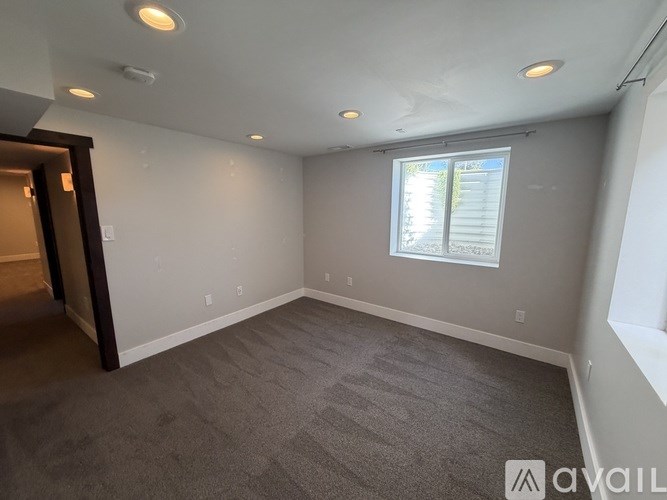 A room with a carpeted floor and a window with blinds.