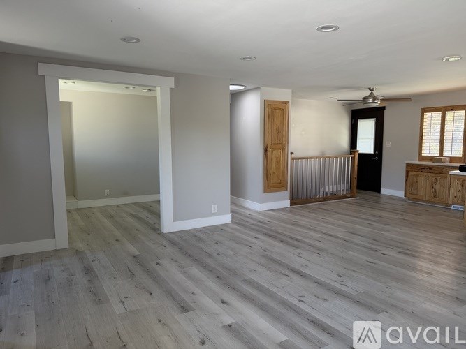 A spacious room with wooden flooring and a ceiling fan.