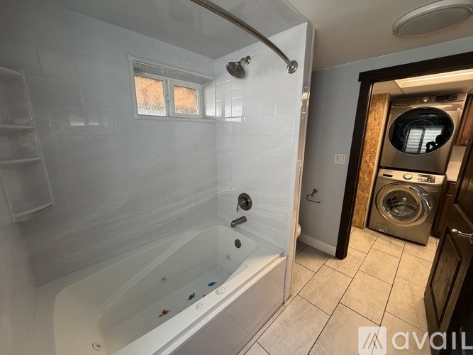 A white bathtub with a shower head and a window above it.